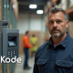 Warehouse supervisor beside the biometric attendance clock, confident the team's hours are captured correctly